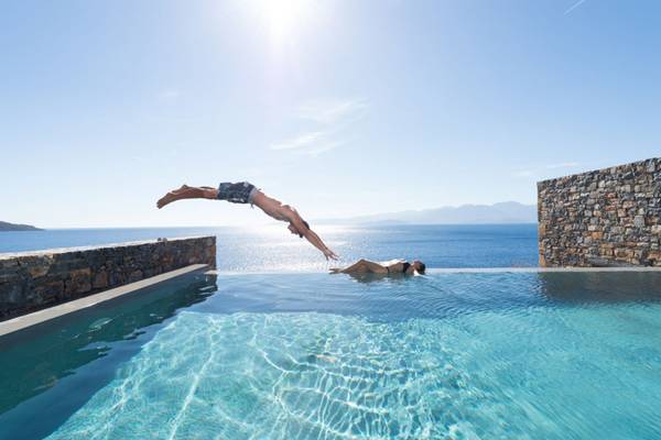 Mann springt ins Schwimmbecken im Elounda Village Resort & Spa