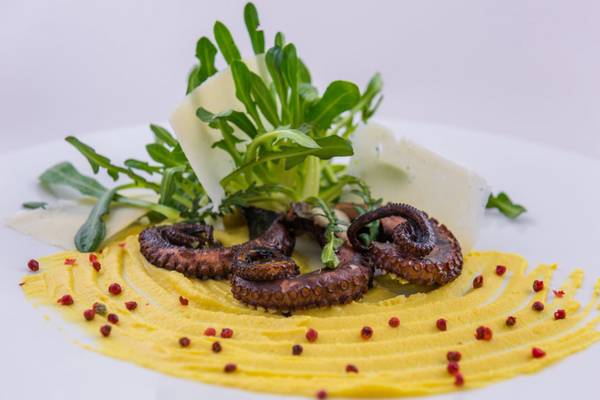 Essen vom Elounda Village Resort & Spa mit Oktopus, gelbem Püree und grünen Blättern.