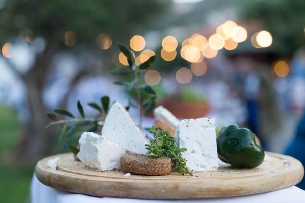 Eine Auswahl an Käse und Gemüse auf einer Holzplatte im Freien im Elounda Village Resort & Spa.
