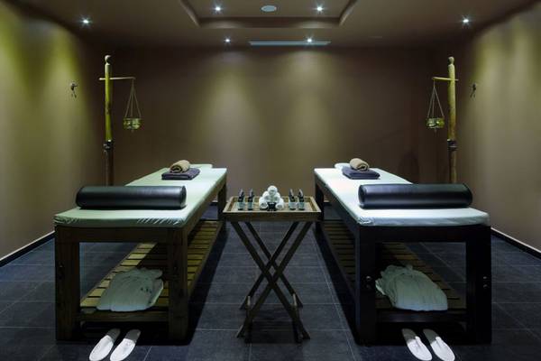 Massagesalon im Elounda Village Resort & Spa mit zwei Behandlungstischen und Massageliegen.