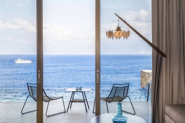 Meerblick aus dem Balkon des Elounda Village Resorts & Spa mit zwei Stühlen und einem Tisch.