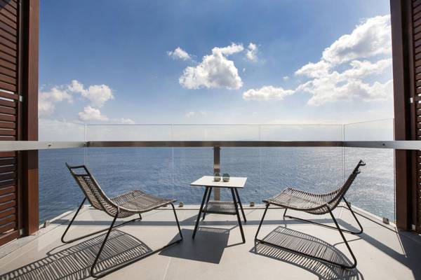 Ein Balkon mit Meerblick im Elounda Village Resort & Spa, mit zwei Stühlen und einem kleinen Tisch.