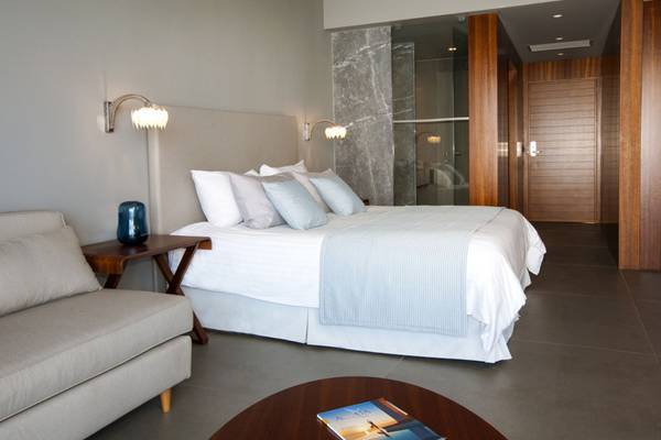 Schlafzimmer im Elounda Village Resort & Spa mit großem Bett, Kissen, Nachttischen und modernem Design.
