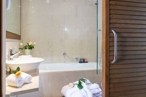 Badezimmer im Elounda Village Resort & Spa mit Badewanne, Waschbecken und Toilettenartikeln.