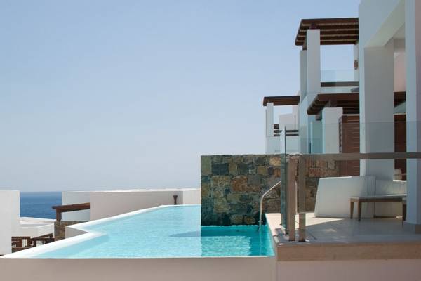 Außenpool mit Steinmauer und Meerblick im Elounda Village Resort & Spa