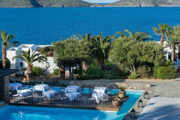 Außenpool mit Tisch und Stuhl-Arrangement im Elounda Village Resort & Spa.