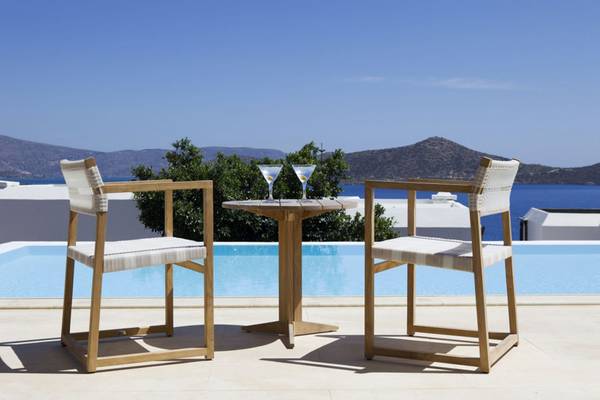 Zwei Holzstühle am Pool mit Cocktails bei Elounda Village Resort & Spa
