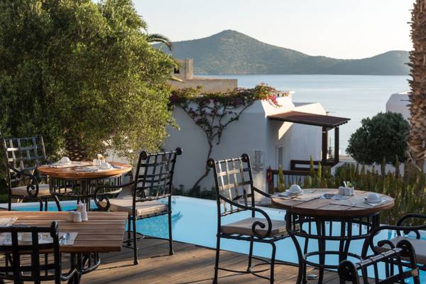 Außenpool-Terrasse mit Tischen und Stühlen im Elounda Village Resort & Spa
