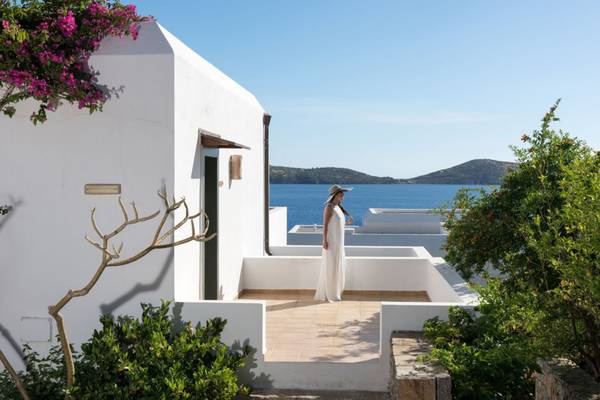 Frau in weißer Robe auf Terrasse von Elounda Village Resort & Spa