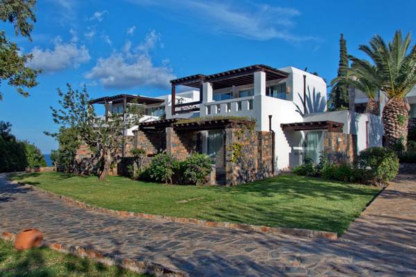 Außenansicht des Elounda Village Resort & Spa mit weißer Architektur und grüner Landschaft