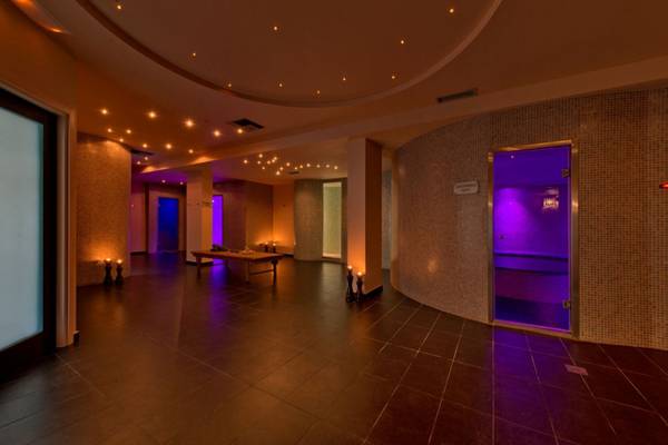 Innenansicht des Saunabereichs im Elounda Village Resort & Spa mit violetten Lichtern und stilvollen Fliesen.