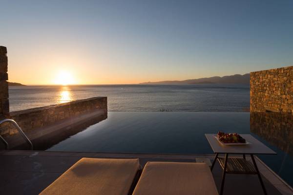 Terrasse des Elounda Village Resort & Spa mit Blick auf das Meer bei Sonnenuntergang.