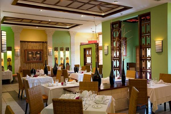 Restaurant im Sanctuary at Grand Memories Varadero mit grünen Wänden und gedeckten Tischen.