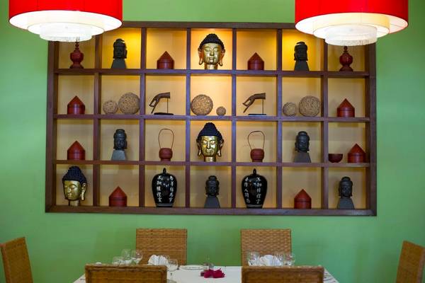 Ein Speisesaal im Sanctuary at Grand Memories Varadero mit grünen Wänden und einem Regal mit Buddha-Skulpturen und anderen Gegenständen.