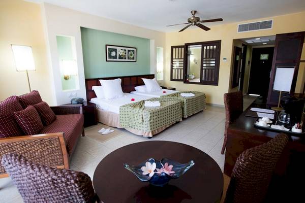 Zimmer im Sanctuary at Grand Memories Varadero Hotel mit zwei Betten, einem Sofa und einem Tisch.