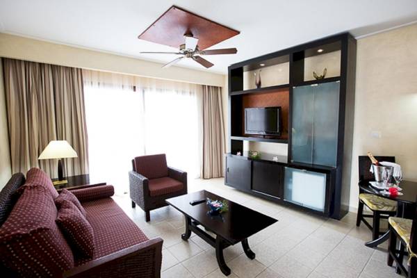 Wohnzimmer mit Fernseher, Sofa, Tisch, Sessel und Deckenventilator