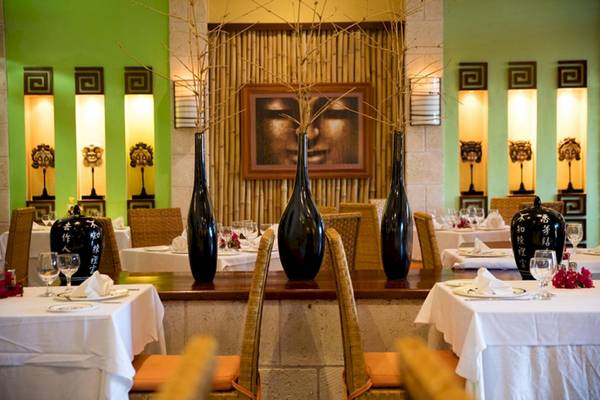 Restaurant-Interieur im Sanctuary at Grand Memories Varadero mit grünen Wänden und schwarzen Vasen.