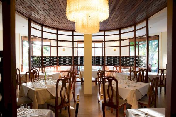 Restaurant des Sanctuary at Grand Memories Varadero mit runden Tischen, Stühlen und einem großen Kronleuchter.