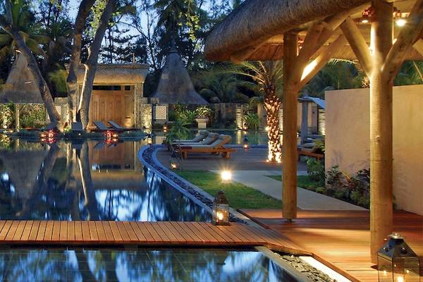 Abendlicher Pool im Shandrani Beachcomber Resort & Spa mit Loungeliegen und stimmungsvoller Beleuchtung.