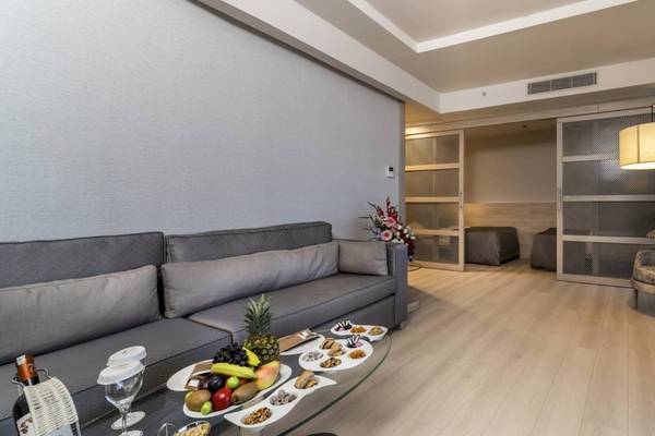 Das Wohnzimmer des Concorde De Luxe Resorts mit grauer Couch, Tisch voller Früchte und Fernseher.
