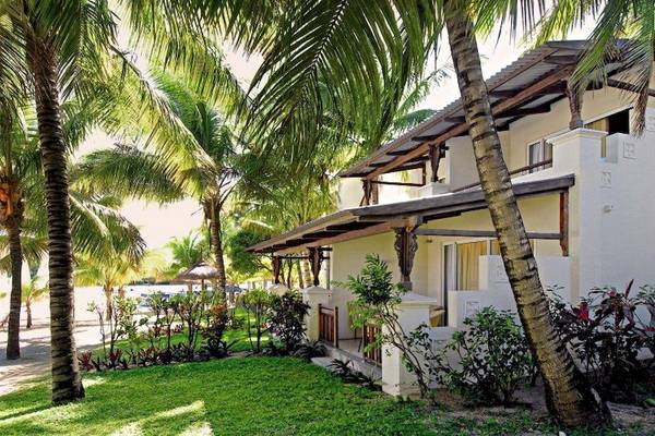 Außenansicht des Shandrani Beachcomber Resorts & Spa mit weißem Gebäude, braunem Dach und grüner Umgebung.