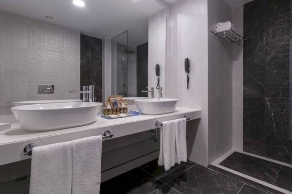 Ein Badezimmer im Concorde De Luxe Resort mit zwei Waschbecken, Spiegel und Marmorboden.