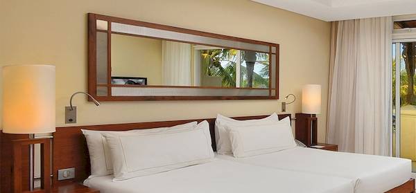 Ein Hotelzimmer mit einem Doppelbett, einem Balkon und Meerblick vom Shandrani Beachcomber Resort.
