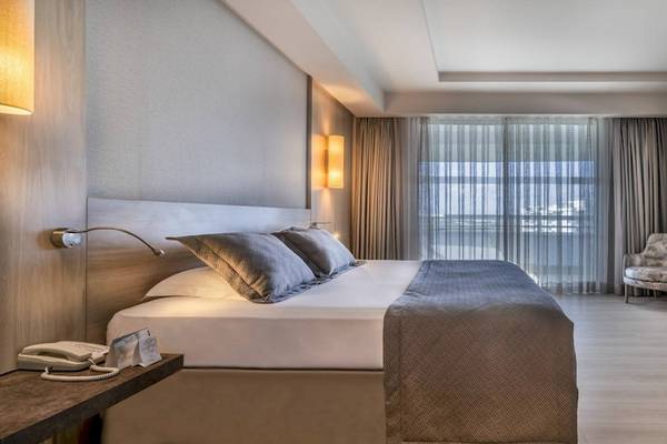Ein modernes Hotelzimmer im Concorde De Luxe Resort mit einem großen Bett, bequemen Sesseln und einer Aussicht auf den Garten.