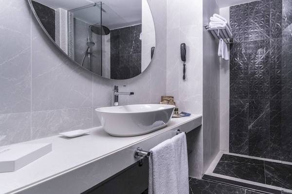 Das Badezimmer des Concorde De Luxe Resorts mit schwarzem Marmor, einer Badewanne und einer Dusche.