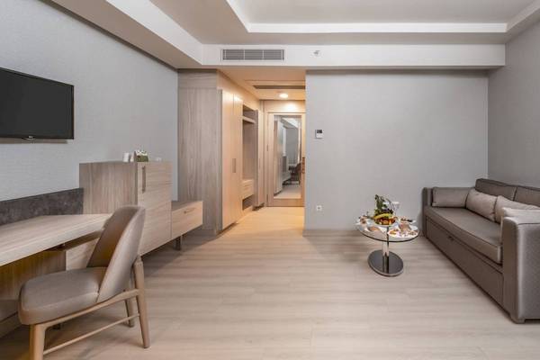 Innenansicht einer Suite im Concorde De Luxe Resort mit Fernseher, Schreibtisch, Stuhl, Sofa und Blumen