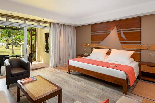 Innenansicht eines Zimmers im Shandrani Beachcomber Resort mit einem Bett, einem Fernseher und einem offenen Balkon.