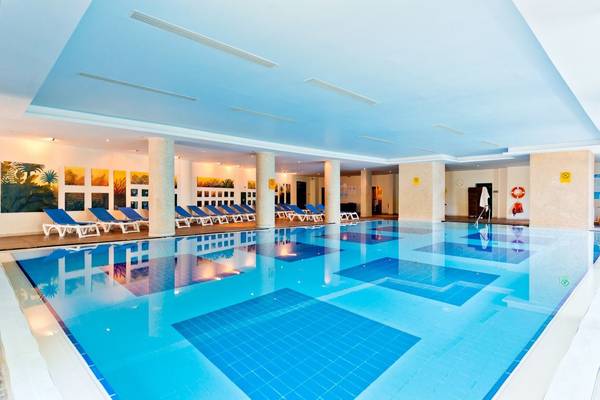 Innenpool des Concorde De Luxe Resorts mit blauen Fliesen und Sonnenliegen
