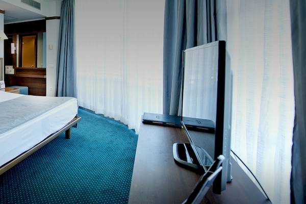 Hotelzimmer im Concorde De Luxe Resort mit Doppelbett, Fernseher, Nachttischen und blauem Teppich.