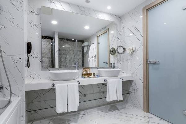 Badezimmer im Concorde De Luxe Resort mit zwei Waschbecken, Badewanne und Spiegel.