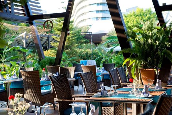 Gartenrestaurant im Concorde De Luxe Resort mit gedeckten Tischen und grüner Pflanzendekoration.