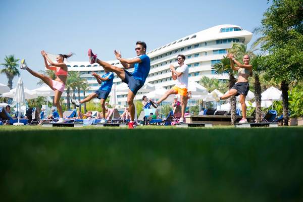 Fitnesskurs im Freien vor dem Concorde De Luxe Resort mit Teilnehmern und Hotel im Hintergrund.