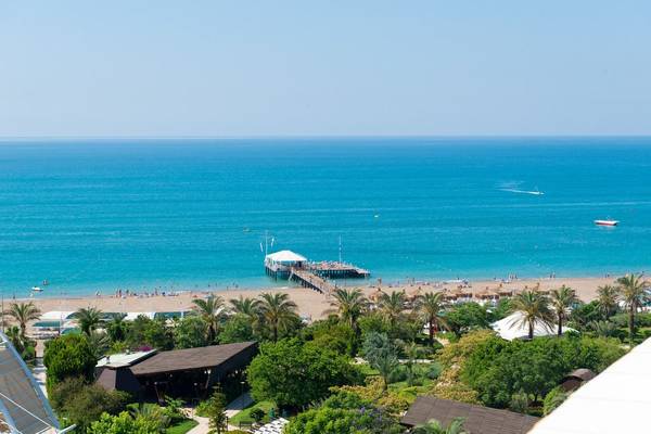 Strandansicht des Concorde De Luxe Resorts mit einer langen, breiten Strandfläche und einem Steg.