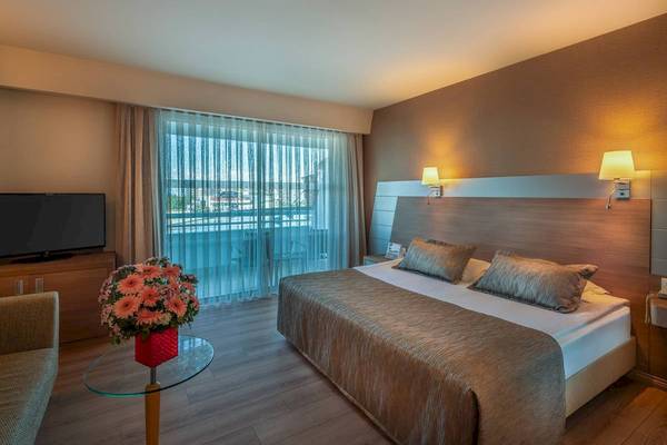 Schlafzimmer im Concorde De Luxe Resort mit Bett, Fernseher und Balkonzugang.