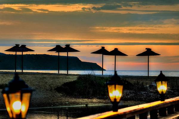 Sonnenuntergang am Kalyves Strand mit Sonnenschirmen auf der Wiese