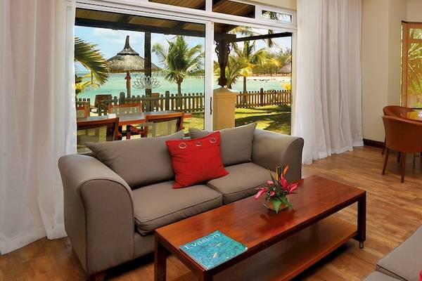 Wohnbereich des Shandrani Beachcomber Resorts mit Blick auf das Meer, inklusive Sofas, Tisch und Essbereich.