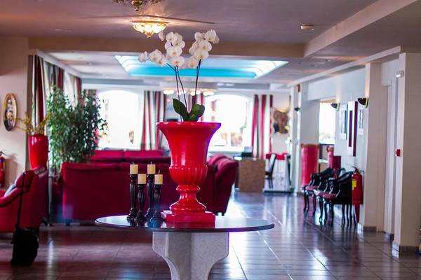 Lobby des Kalyves Beach Hotels mit rotem Vasen-Arrangement und Möbeln.