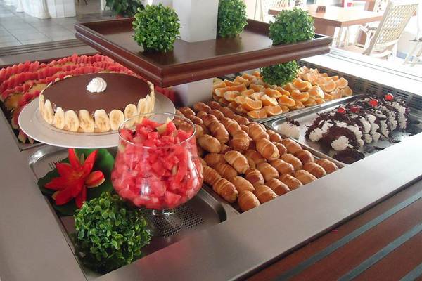 Buffet-Tisch im Kalyves Beach Hotel mit verschiedenen Desserts, Früchten und Getränken.