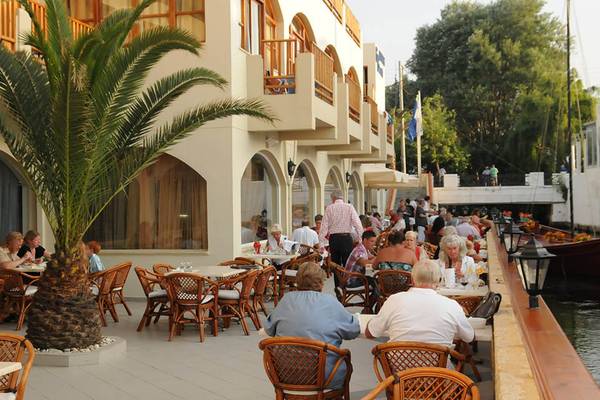 Gäste sitzen an Tischen auf der Terrasse des Kalyves Beach Hotels.