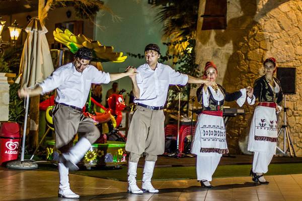 Ein Paar tanzt traditionell auf der Bühne im Freien des Kalyves Beach Hotels.