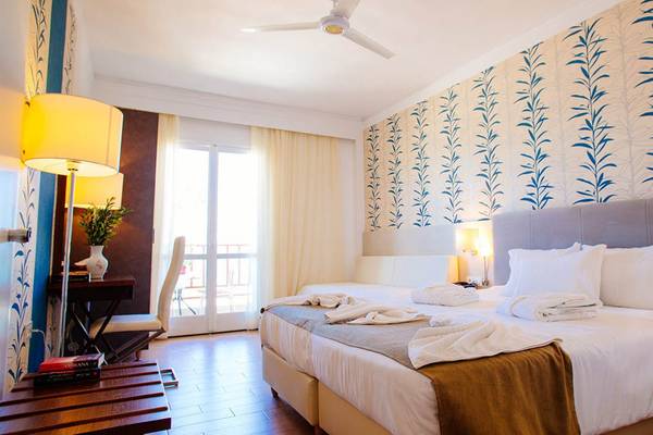 Innenansicht eines Doppelzimmers im Kalyves Beach Hotel mit blau-weißem Wandmuster und zwei Betten.