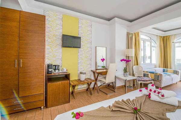 Innenansicht eines Zimmers im Kalyves Beach Hotel mit Bett, Schreibtisch, Fernseher und Möbeln.