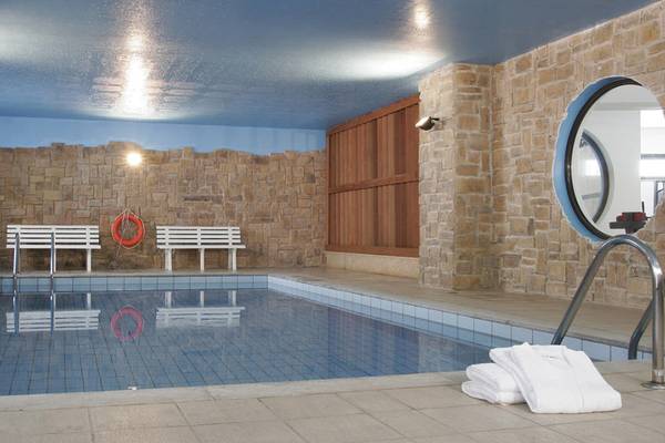 Innenpool des Hersonissos Maris Hotels mit weißen Bänken, Rettungsring und blauer Decke.