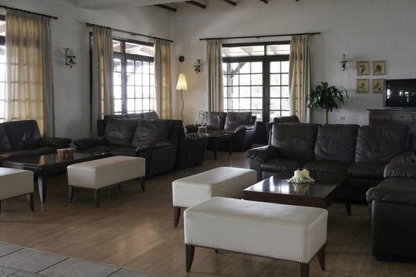 Lobby des Hersonissos Maris Hotels mit schwarzen Ledersofas, weißen Beistelltischen und einer Lampe.