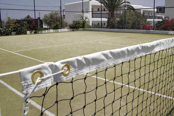 Tennisplatz im Hersonissos Maris Hotel, umgeben von Gebäuden und Pflanzen.