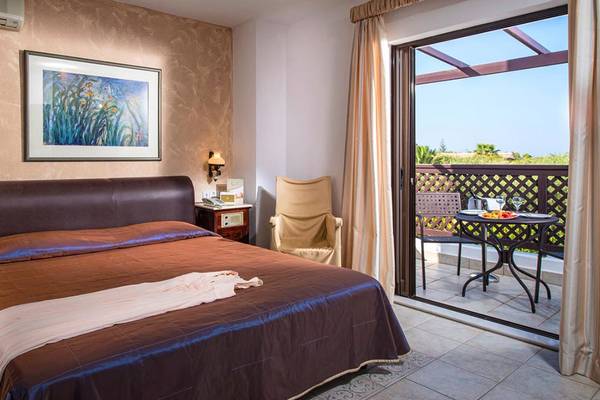 Ein komfortables Schlafzimmer im Hersonissos Maris Hotel mit einem großen Bett, einem Balkon und einer malerischen Aussicht.